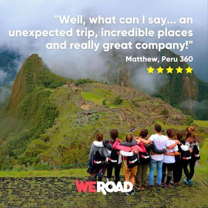 A WeRoad group trip stands with arms around each other, looking out over an ancient mountain citadel on a misty day.
