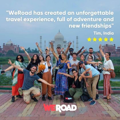 A WeRoad group trip of travelers posing and smiling for a photo in front of the Taj Mahal.
