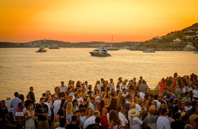 Un viaggio di gruppo WeRoad si riunisce in riva al mare al tramonto, con yacht sull'acqua e una costa sullo sfondo.