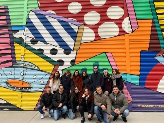 Foto di gruppo sotto ad un murales colorato, in New York a maggio - WeRoad