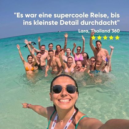 Eine Frau macht ein Selfie mit einer WeRoad-Gruppe, die posiert und winkt, während sie im klaren, türkisfarbenen Wasser steht.
