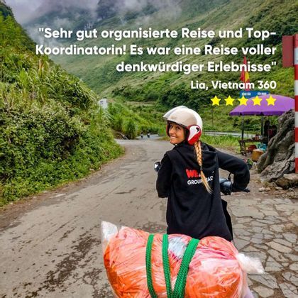 Ein WeRoad Reiseleiter mit Helm lächelt auf einem Roller auf einer kurvenreichen Straße durch üppig grüne Berge.