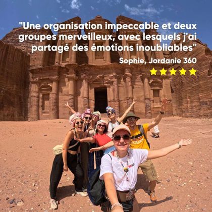 Un groupe WeRoad prend un selfie souriant devant un grand monument antique sculpté dans une paroi rocheuse désertique.
