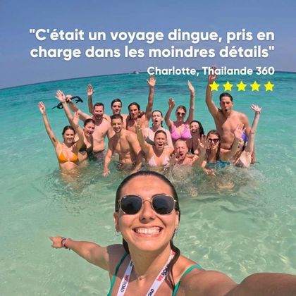 Une femme souriante prend un selfie avec un groupe WeRoad en voyage, acclamant et saluant dans une eau turquoise claire.