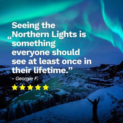 A silhouette of a person with arms raised stands on a snowy cliff, watching a waterfall under the Northern Lights.