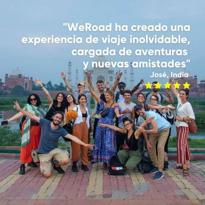 Un viaje en grupo de WeRoad con personas sonrientes posando para una foto frente a un gran mausoleo de mármol blanco.