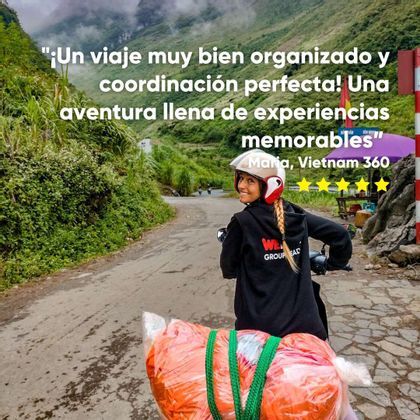 Una mujer en un viaje en grupo de WeRoad sonríe al conducir una scooter por una carretera pavimentada a través de un paisaje exuberante, verde y montañoso.
