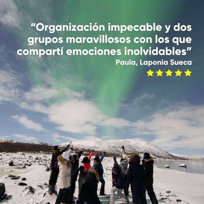 Un grupo de WeRoad con abrigos de invierno en un paisaje nevado, señalando las auroras boreales verdes en el cielo.