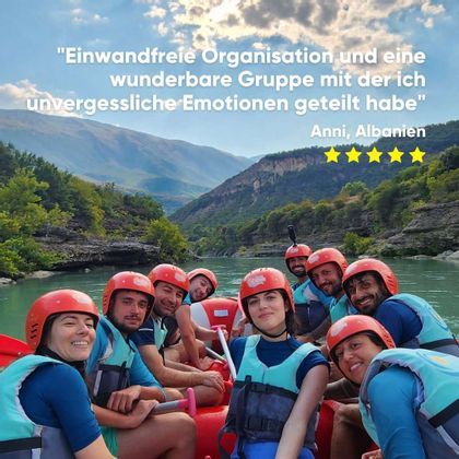 Eine WeRoad-Gruppe mit Helmen und Schwimmwesten lächelt für ein Foto beim Rafting auf einem Fluss in einer Bergschlucht.