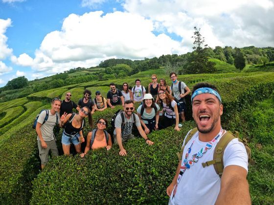 Un hombre se toma una selfie sonriente con su grupo de WeRoad en una exuberante plantación de té verde.