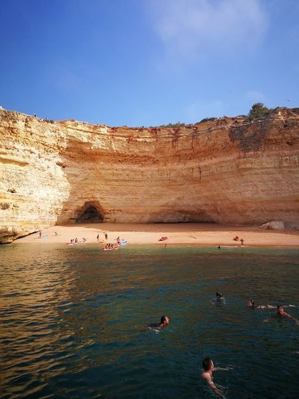 Un viaggio di gruppo WeRoad nuota e fa kayak nel mare di una caletta sabbiosa incastonata sotto un'imponente scogliera.
