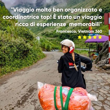 Una donna in un viaggio di gruppo WeRoad sorride mentre guida uno scooter su una strada tortuosa attraverso un paesaggio lussureggiante e verde.