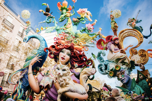 Una scultura falla molto grande e colorata con figure intricate di persone e animali esposta in una strada cittadina.