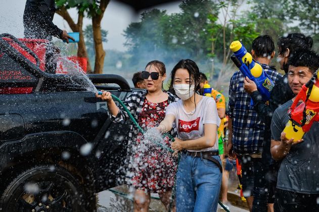Un viaggio di gruppo WeRoad: persone che fanno una battaglia d'acqua all'aperto con una canna e pistole ad acqua, accanto a un camion.