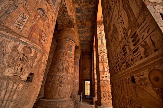 El interior de un templo antiguo con columnas de piedra macizas cubiertas de coloridos jeroglíficos egipcios.