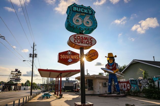 Vintage-Straßenschilder für die Route 66, Souvenirs und Spielzeug, mit einer großen Space-Cowboy-Statue vor einem Gebäude.