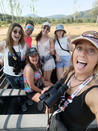 Una mujer con binoculares se toma una selfie de su viaje en grupo de WeRoad en la parte trasera de un vehículo al aire libre.
