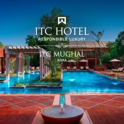 L'hotel ITC Mughal ad Agra, con una grande piscina circondata da un patio in mattoni rossi, un pergolato e giardini lussureggianti.