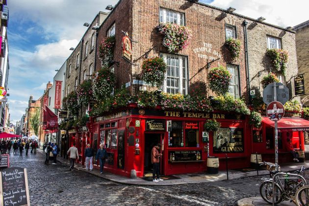 El pub Temple Bar de Dublín, con su fachada roja decorada con flores y gente paseando por la calle adoquinada.