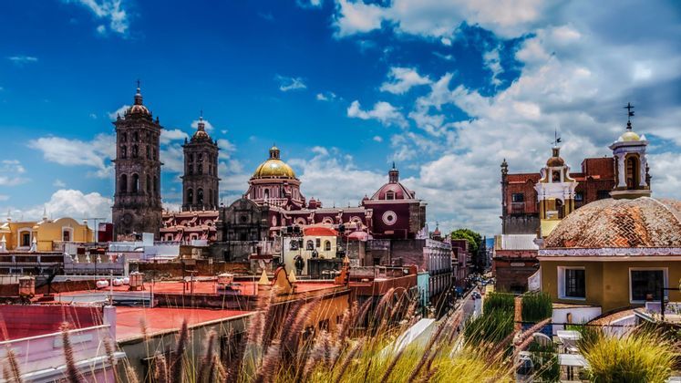 Un panorama urbano con campanili di chiesa decorati e cupole colorate, osservato sui tetti sotto un cielo azzurro luminoso.