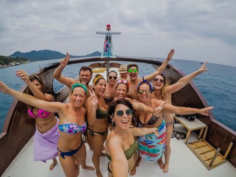 Un viaje en grupo de WeRoad con personas en traje de baño posando para una selfie en la cubierta de un barco en el mar.