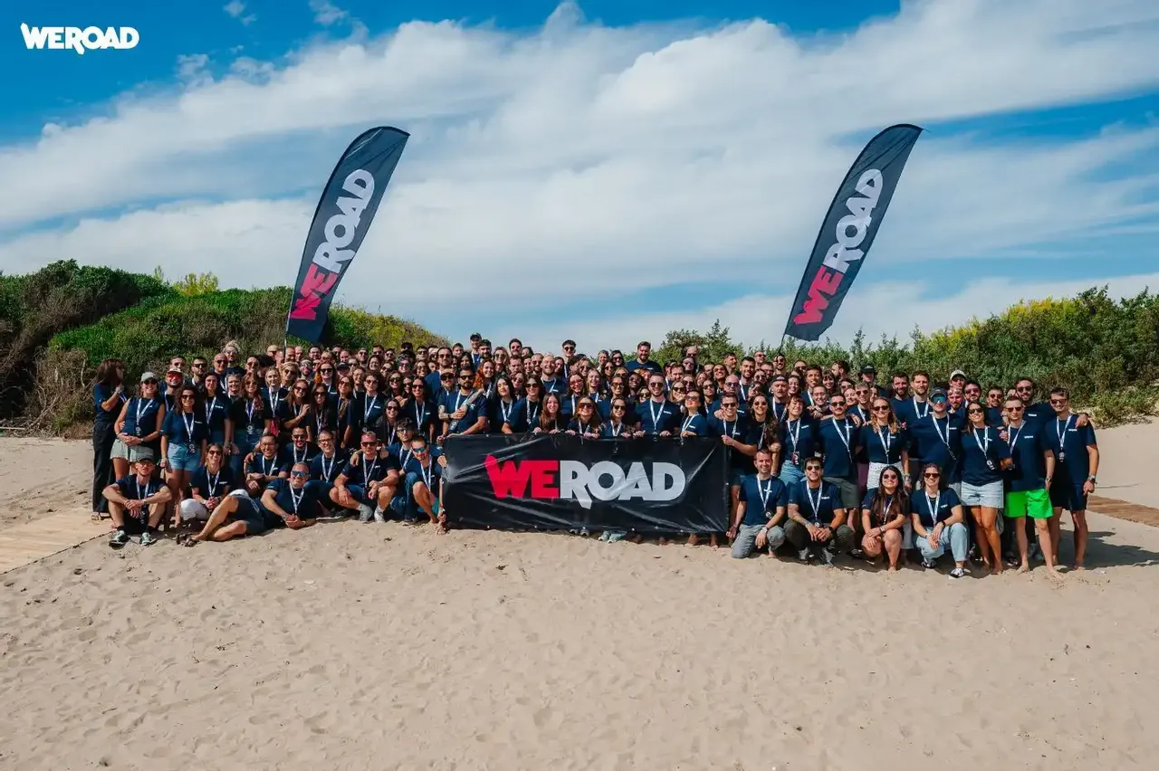 Il team WeRoad in spiaggia con le bandiere WeRoad