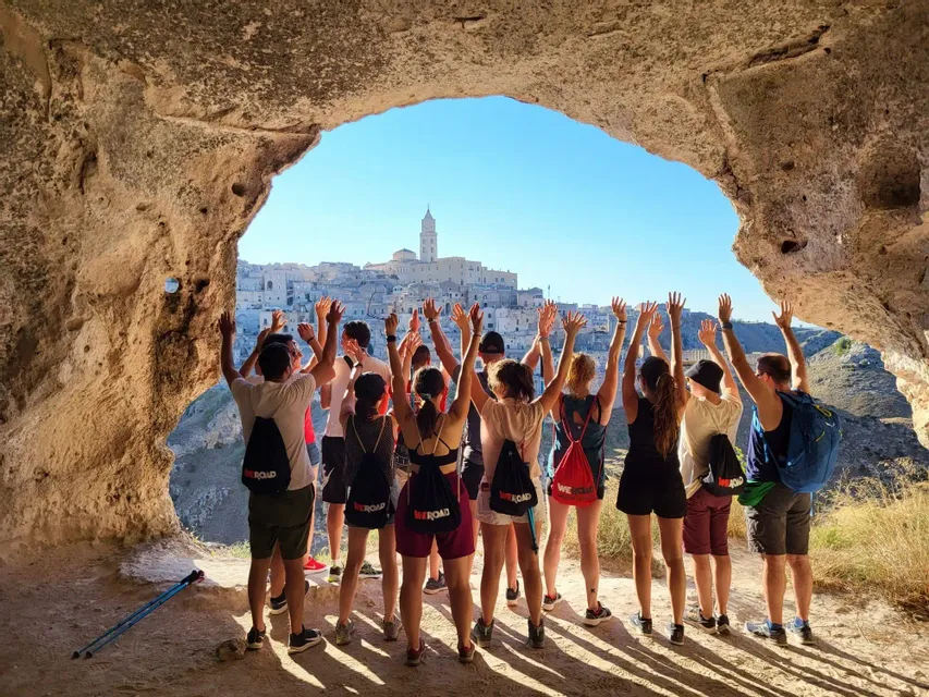 Gruppo di viaggiatori con le braccia alzate davanti a Matera