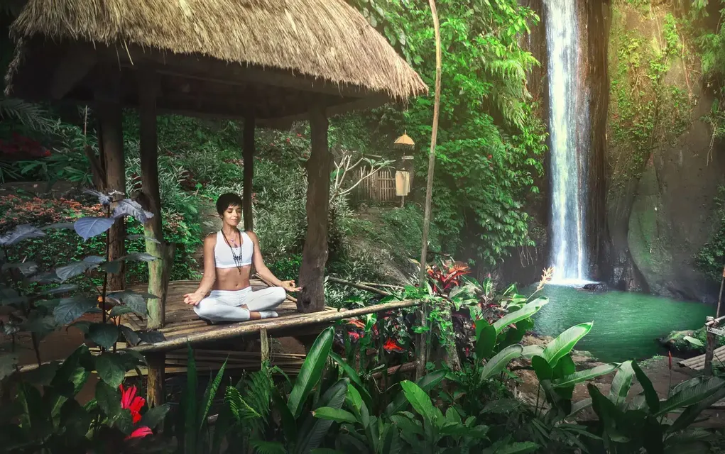 Persona in meditazione in un padiglione davanti a una cascata