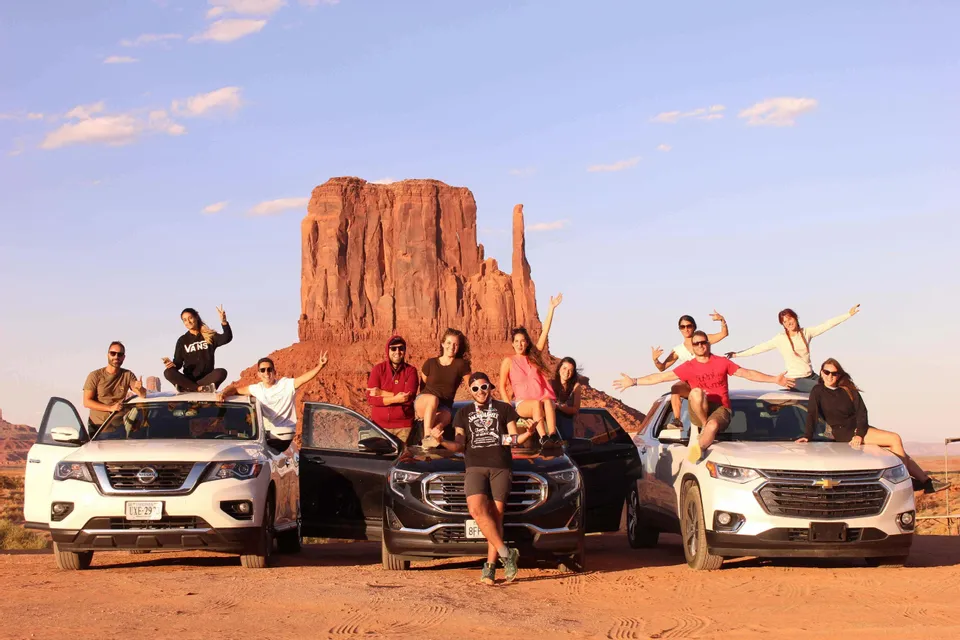 Gruppo di viaggiatori accanto alle auto in un deserto di rocce rosse