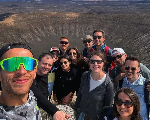 Un gruppo WeRoad si scatta un selfie sul bordo di un grande cratere vulcanico.