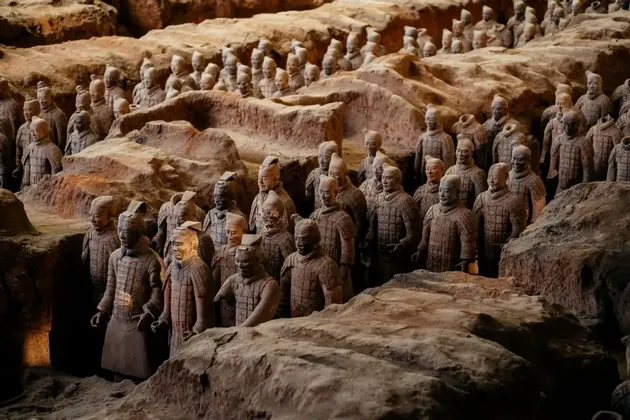 File di statue di guerrieri di terracotta in formazione in una fossa archeologica scavata.