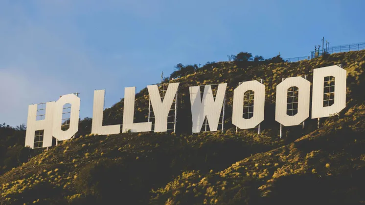La grande insegna bianca di Hollywood si trova su una collina erbosa sotto un cielo azzurro e limpido.