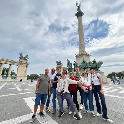 Un viaggio di gruppo WeRoad in posa in una grande piazza cittadina davanti a un alto monumento con statue