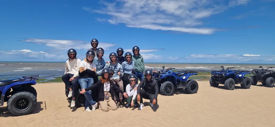 Un grupo de WeRoad con cascos posa para una foto en una playa de arena junto a sus quads.