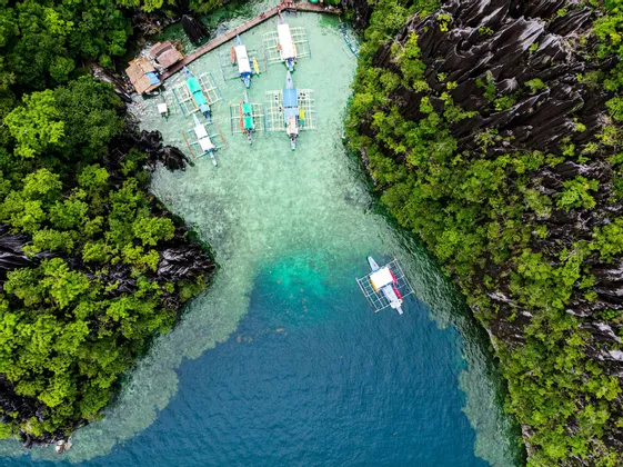 Vista aerea di piroghe tradizionali in una laguna turchese circondata da scogliere rocciose e lussureggianti