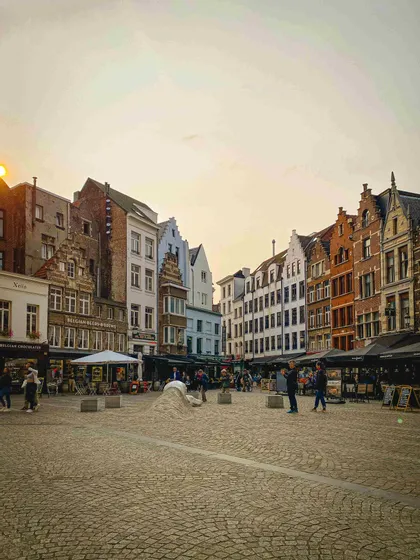 Una piazza cittadina acciottolata, circondata da tradizionali edifici a capanna e caffè all'aperto, durante un caldo tramonto.