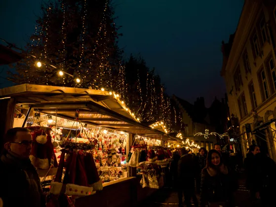 Un vivace mercatino di Natale di notte, con bancarelle illuminate da lucine che vendono decorazioni festive ai clienti.