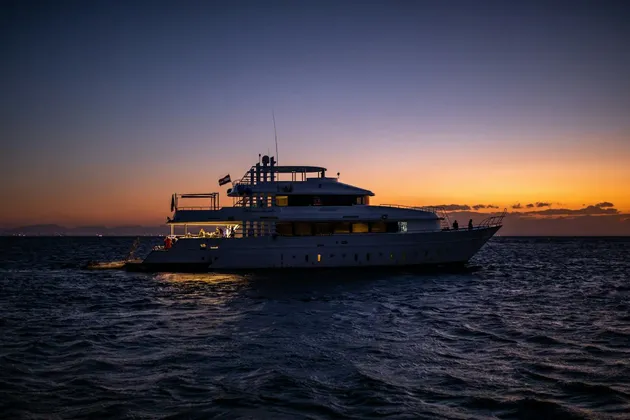 A WeRoad group trip on an illuminated yacht cruising on the open sea during a colorful sunset.