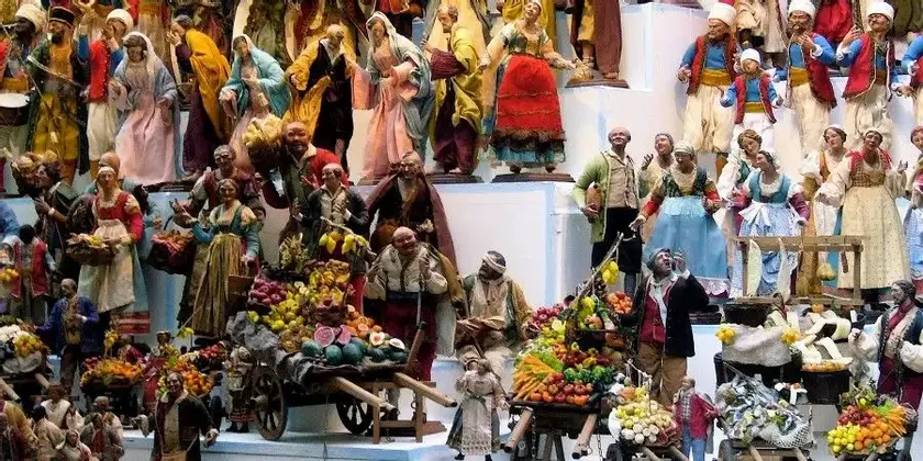 Una concurrida colección de figuras detalladas con vestimenta tradicional que representan un mercado bullicioso con puestos de frutas.