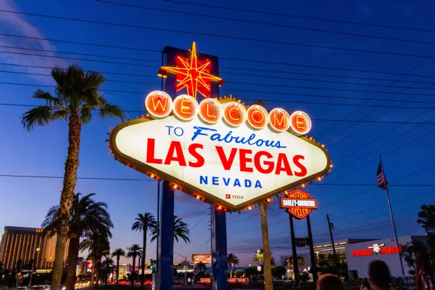 Il cartello 'Welcome to Fabulous Las Vegas' illuminato da luci al neon contro un cielo crepuscolare con palme.
