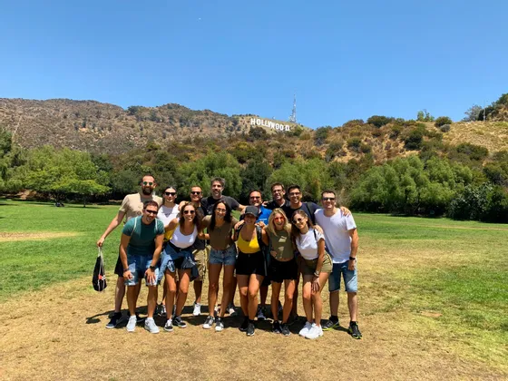 Eine WeRoad-Gruppenreise posiert gemeinsam für ein Foto auf einer grasbewachsenen Wiese mit dem Hollywood-Schriftzug auf einem Hügel im Hintergrund.