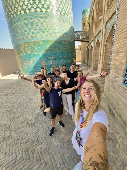 Un gruppo WeRoad si scatta un selfie su una strada lastricata, accanto a una grande torre piastrellata di turchese.