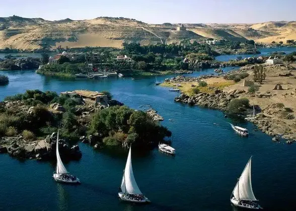 Un viaggio di gruppo WeRoad a bordo di diverse barche a vela bianche, che navigano un ampio fiume blu tra isole lussureggianti e colline sabbiose.