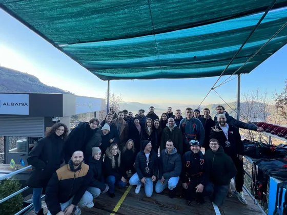 Un gruppo WeRoad in viaggio posa per una foto di gruppo su una piattaforma esterna con colline sullo sfondo.