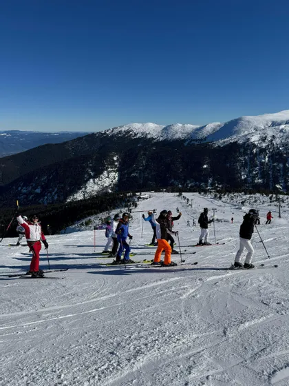 Un groupe WeRoad en tenue de ski complète posant sur une piste enneigée sous un ciel bleu clair.