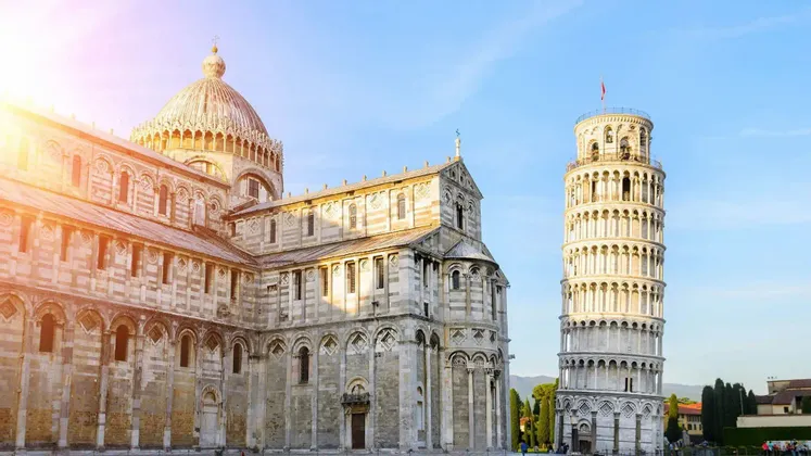 La Torre Pendente di Pisa e il Duomo di Pisa si ergono sotto il sole splendente contro un cielo azzurro limpido.