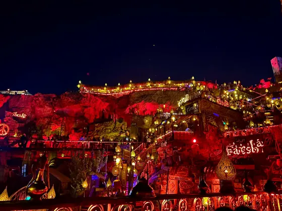 Una location all'aperto su più livelli, ricavata in una parete rocciosa, illuminata di notte da centinaia di lampade e lanterne dai toni caldi.