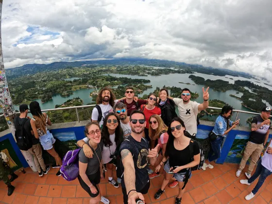 Un voyage en groupe WeRoad prend un selfie sur une terrasse d'observation avec une vue panoramique sur des lacs et des îles verdoyantes et vallonnées.