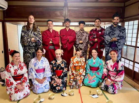 Un gruppo WeRoad in viaggio, con indosso kimono e yukata tradizionali, posa insieme in una stanza giapponese con tatami.