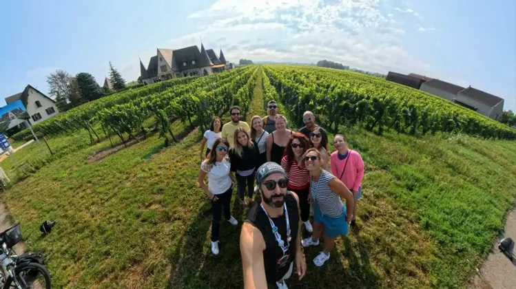 Ein Mann macht ein Selfie seiner WeRoad Gruppenreise, gemeinsam auf einem Weg zwischen Weinreben in einem Weinberg posierend.
